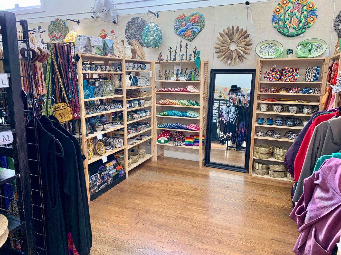 Wooden shelves of bowls, cups and beaded jewelry under a row of cut-metal wall art