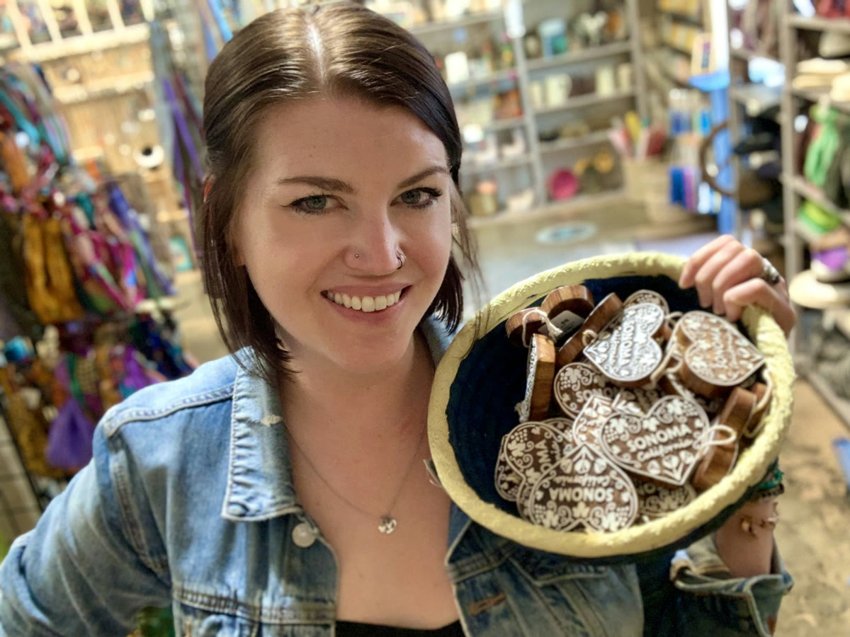 Sofie Burt in the shop, holding a basket of carved Sonoma heart ornaments